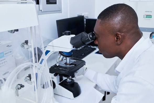 a lab technician looking into a microscope